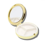 Round yellow and gold pill compact open, showing mirror lid and three-compartment white interior tray.