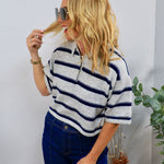 Woman wearing grey and navy striped cropped polo sweater top with dark wash jeans and oversized sunglasses
