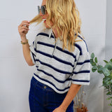 Woman wearing grey and navy striped cropped polo sweater top with dark wash jeans and oversized sunglasses
