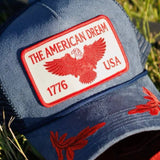 Navy blue trucker hat with red American Dream 1776 USA eagle patch and red floral brim embroidery
