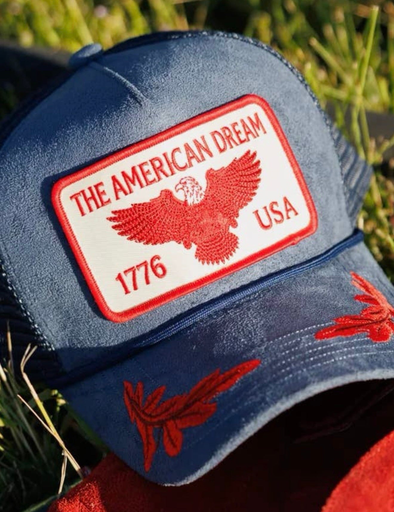 Navy blue trucker hat with red American Dream 1776 USA eagle patch and red floral brim embroidery