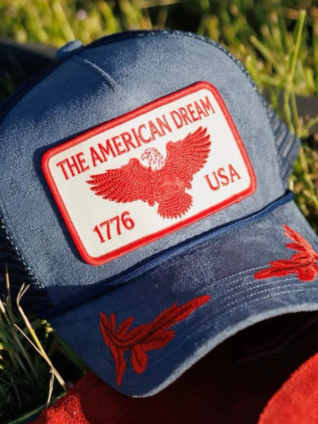Navy blue trucker hat with red American Dream 1776 USA eagle patch and red floral brim embroidery
