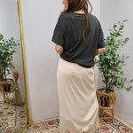 Cream satin midi skirt with lace hem, styled with charcoal t-shirt and red heels, back view.