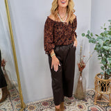 Dark chocolate brown faux leather cropped wide-leg pants with elastic waistband, styled with paisley off-shoulder top and tan