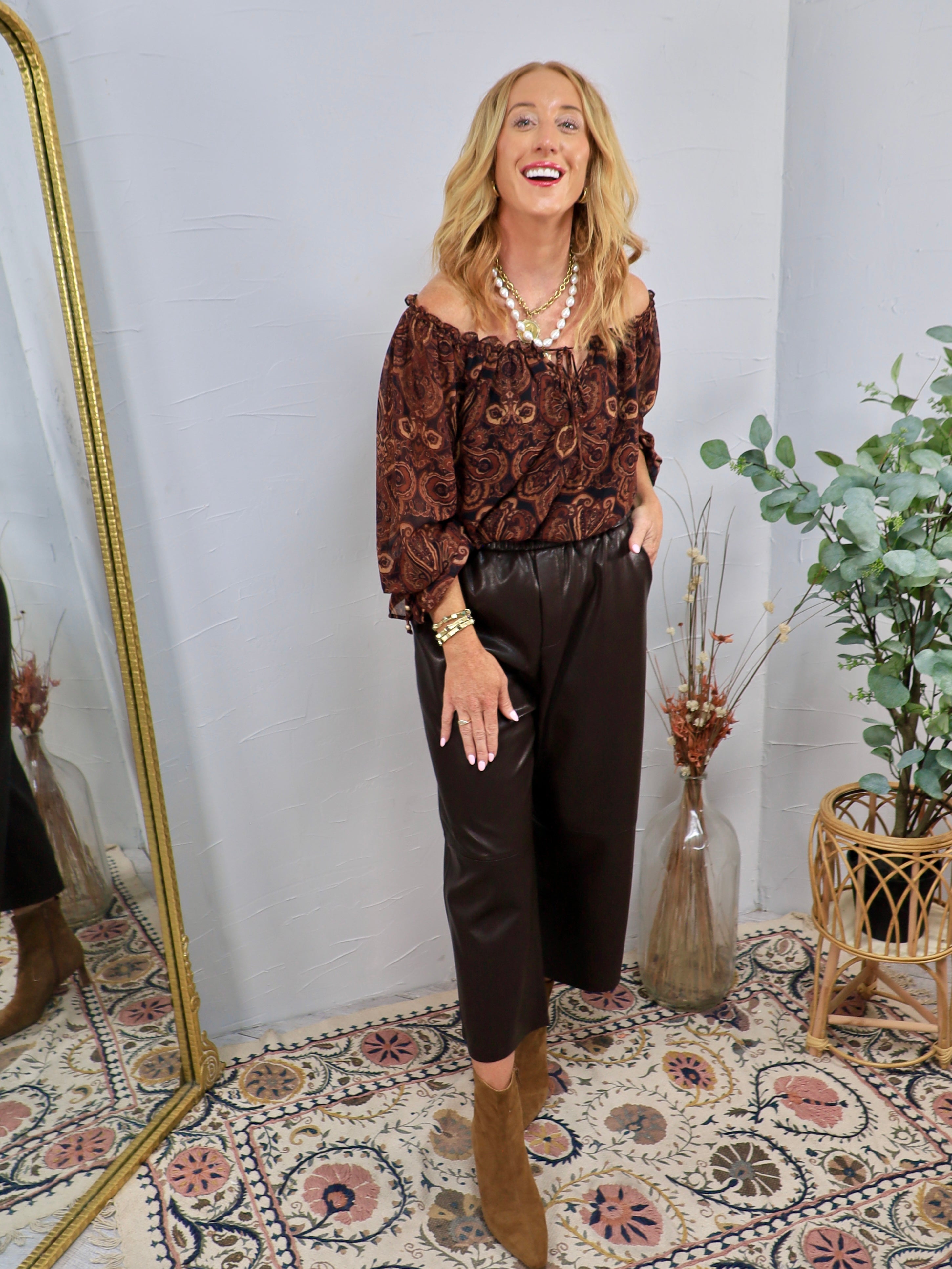 Dark chocolate brown faux leather cropped wide-leg pants with elastic waistband, styled with paisley off-shoulder top and tan