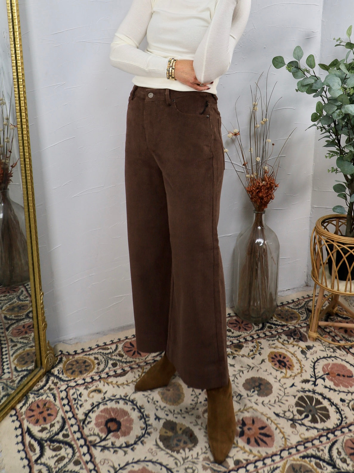 Woman wearing chocolate brown wide-leg corduroy pants with white turtleneck and tan ankle boots