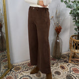Woman wearing chocolate brown wide-leg corduroy pants with white turtleneck and tan ankle boots