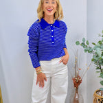 Woman wearing royal blue and white striped polo long sleeve top with white wide-leg jeans