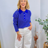 Woman wearing royal blue and white striped polo long sleeve top with white wide-leg jeans
