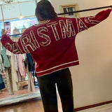 Model wearing red Christmas crewneck sweatshirt with bold festive letter appliqués across the back