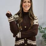 Brown and cream geometric patterned cardigan with gold buttons, layered over dark turtleneck, modeled by smiling woman.