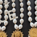 Pearl beaded necklace with gold coin pendant engraved "Love Each Other More," adorned with crystal halo border.