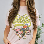 Woman wearing light pink graphic tee with vintage cowboy design and Well Sheeyit text