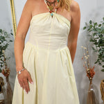 Woman wearing yellow halter maxi dress with beaded necklace styling, featuring gathered bodice and flowing skirt in bohemian 