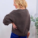 Charcoal brown crewneck sweater with ribbed hem, shown from back, styled with blue wide-leg jeans.