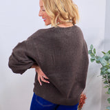 Charcoal brown crewneck sweater with ribbed hem, shown from back, styled with blue wide-leg jeans.