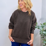 Chocolate brown oversized crewneck sweater styled with blue wide-leg jeans, featuring ribbed cuffs and hem.