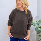 Chocolate brown oversized crewneck sweater styled with blue wide-leg jeans, featuring ribbed cuffs and hem.