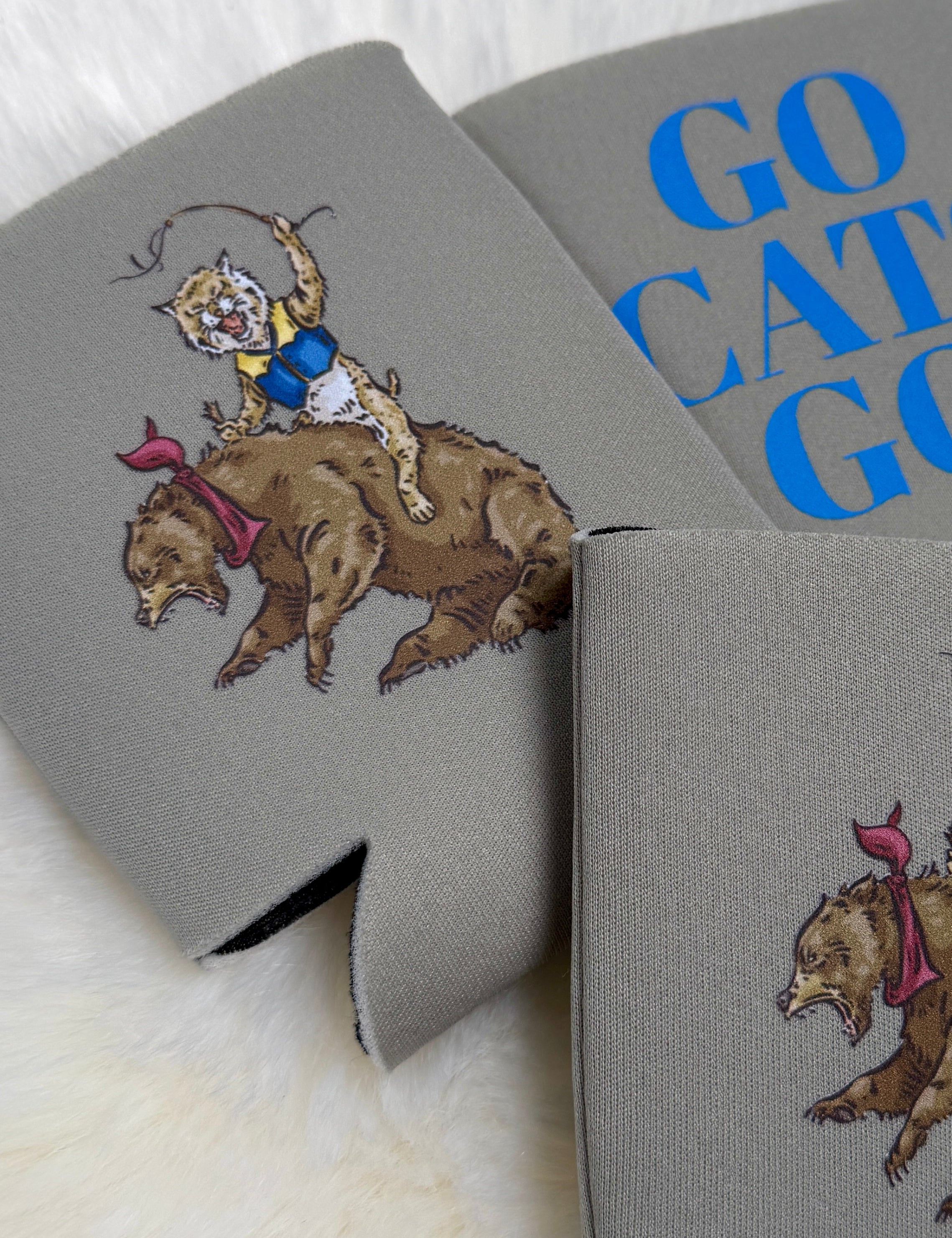 Gray neoprene koozie featuring illustrated wildcat riding a bear, with "Go Cats Go" text in blue.