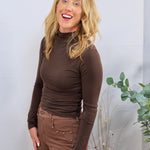 Chocolate brown long-sleeve mock turtleneck top, fitted silhouette, styled with matching brown studded pants.