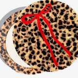 Round compact mirror with leopard print tortoiseshell design and decorative red ribbon bow accent.