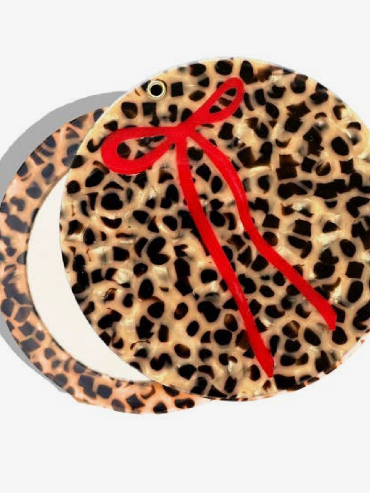 Round compact mirror with leopard print tortoiseshell design and decorative red ribbon bow accent.