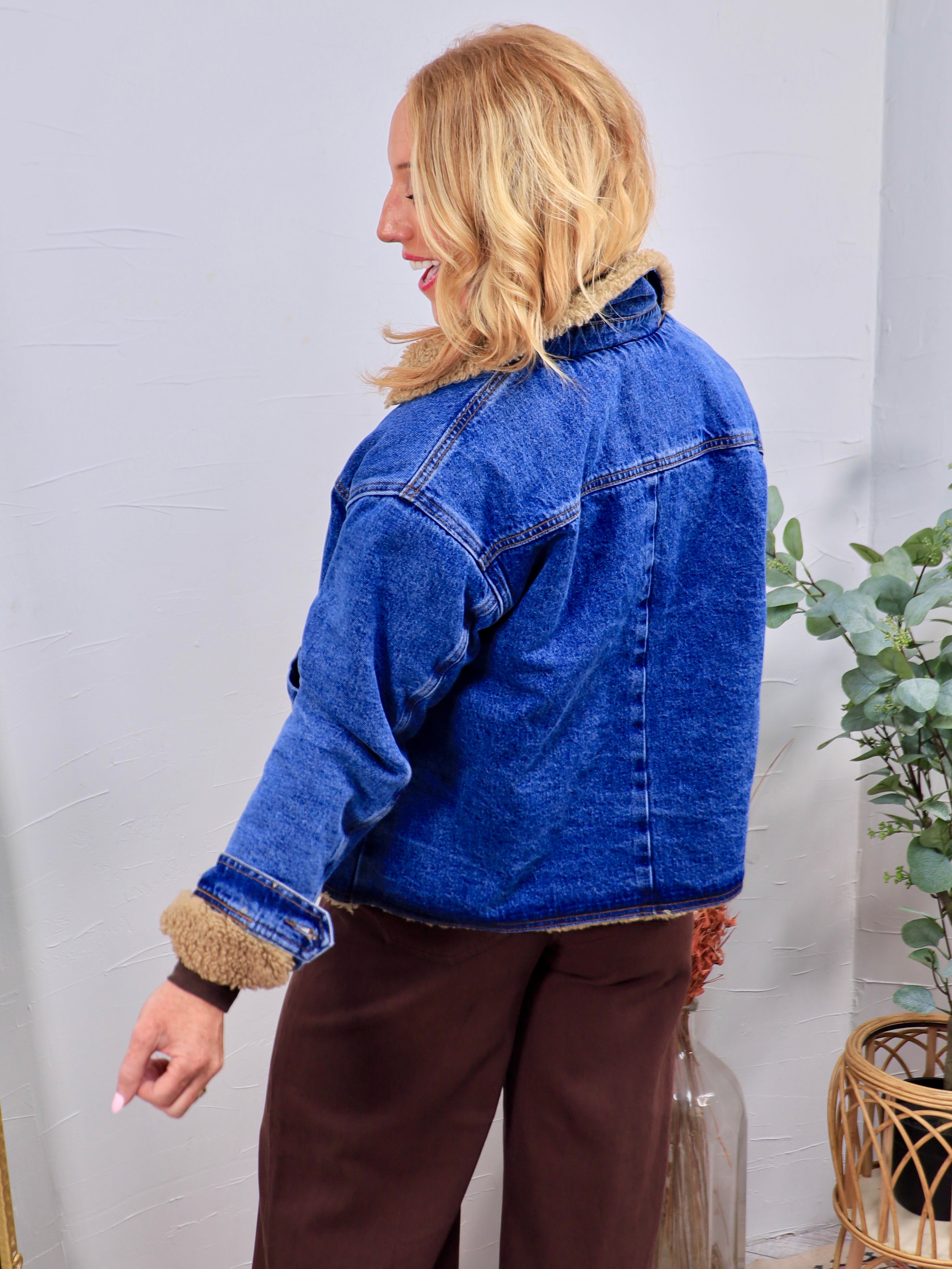 Blue denim Graham Teddy Jacket with tan sherpa lining, collar, and cuffs, styled with brown wide-leg pants.