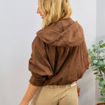 Brown hooded bomber jacket with voluminous sleeves, styled with khaki pants, shown from back angle.