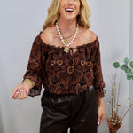 Brown and black paisley off-shoulder blouse with ruffle neckline, tie detail, and three-quarter sleeves.