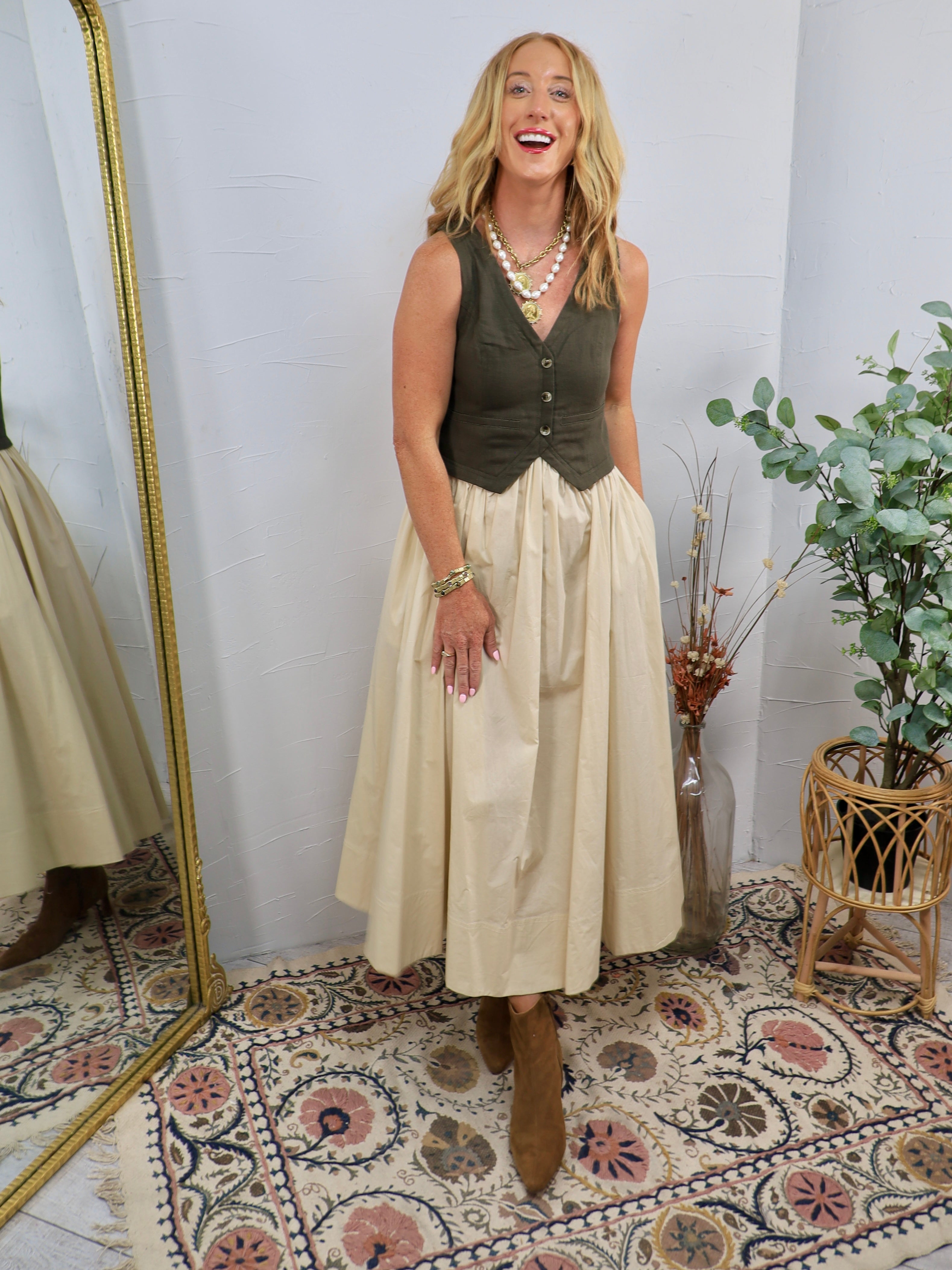Olive green button-front vest bodice midi dress with cream full skirt, styled with brown ankle boots and layered gold necklac