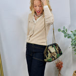Woman wearing a cream ribbed double-layered button-front top with dark jeans and a camo crossbody bag