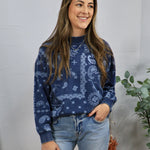 Woman wearing navy blue paisley print crewneck sweatshirt with light wash jeans, smiling