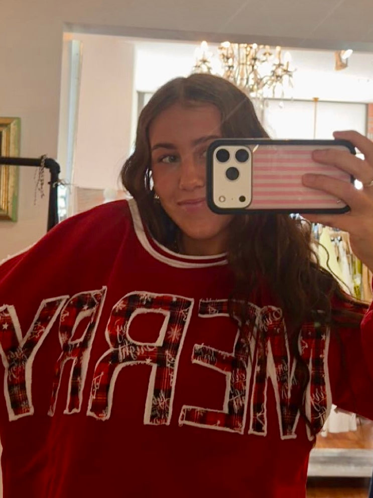Red "MERRY" crewneck sweatshirt with plaid lettering and white trim, styled oversized in mirror selfie.