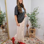 Cream lace midi skirt styled with charcoal graphic tee and red cowboy boots, full length silhouette.
