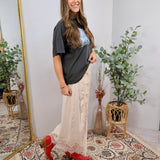 Cream lace midi skirt styled with charcoal graphic tee and red cowboy boots, full length silhouette.