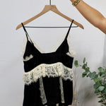 Black spaghetti strap camisole top with cream lace trim detailing at neckline and waist ruffle.
