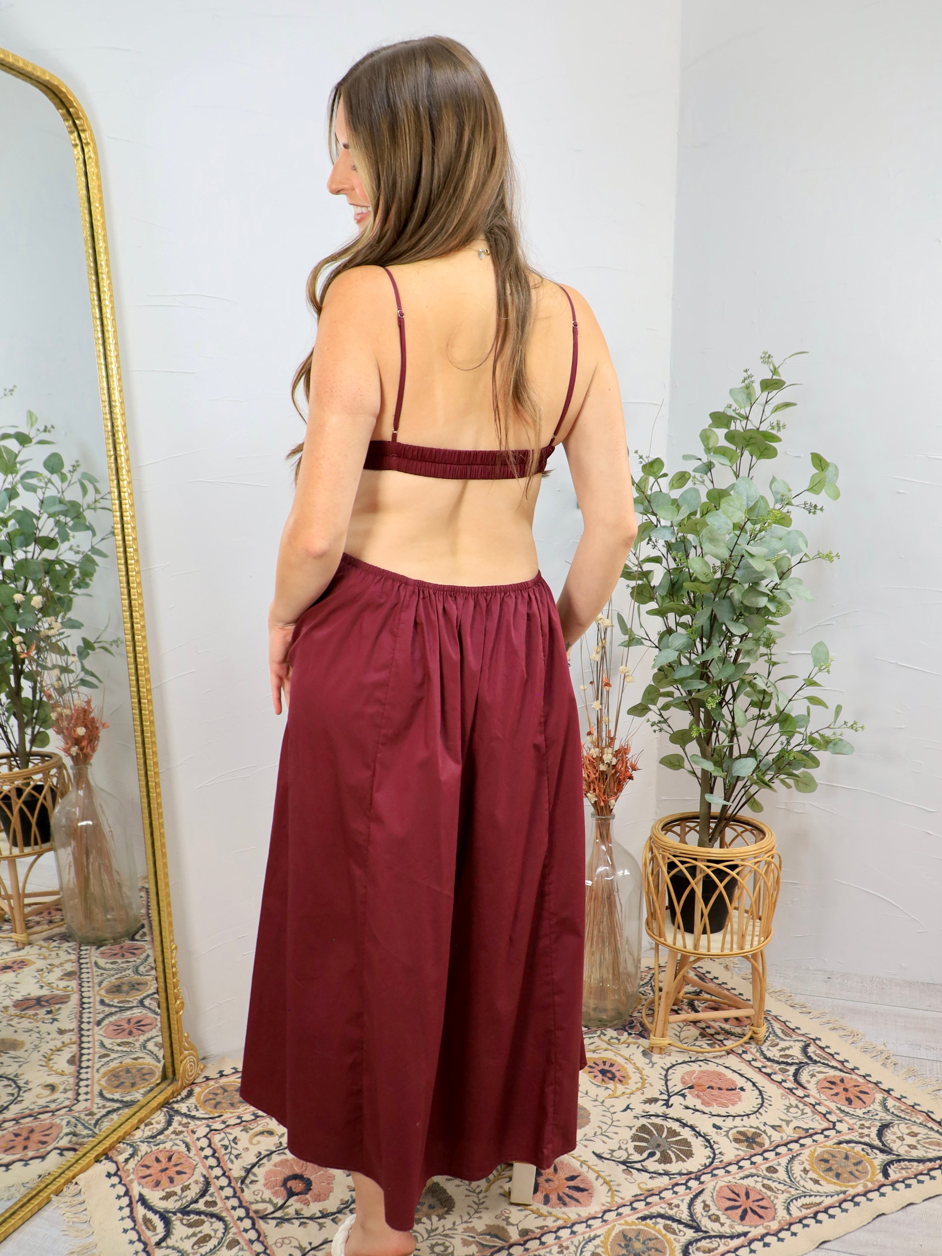Backless plum maxi dress with spaghetti straps, ruched bralette top, and wide-leg palazzo pants silhouette.