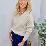 Oatmeal beige V-neck knit sweater styled with dark blue jeans and layered pearl chain necklace.