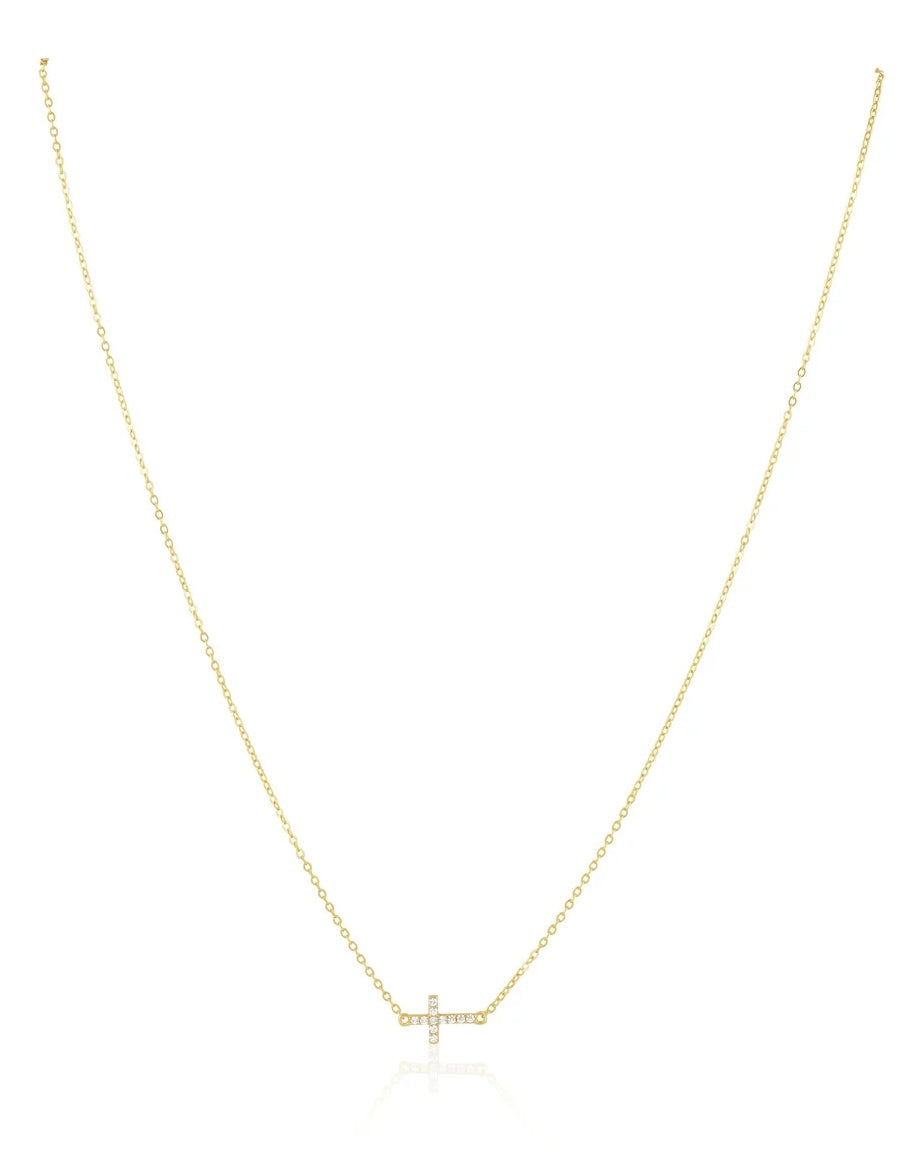 Gold delicate cable chain necklace with pavé crystal sideways cross pendant on white background