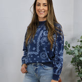 Navy blue paisley print crewneck sweater styled with light wash jeans, featuring long sleeves and white pattern detailing.