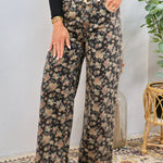Wide-leg floral print denim jeans in dark black with dusty rose and sage blooms, styled with black long-sleeve top and tan booties