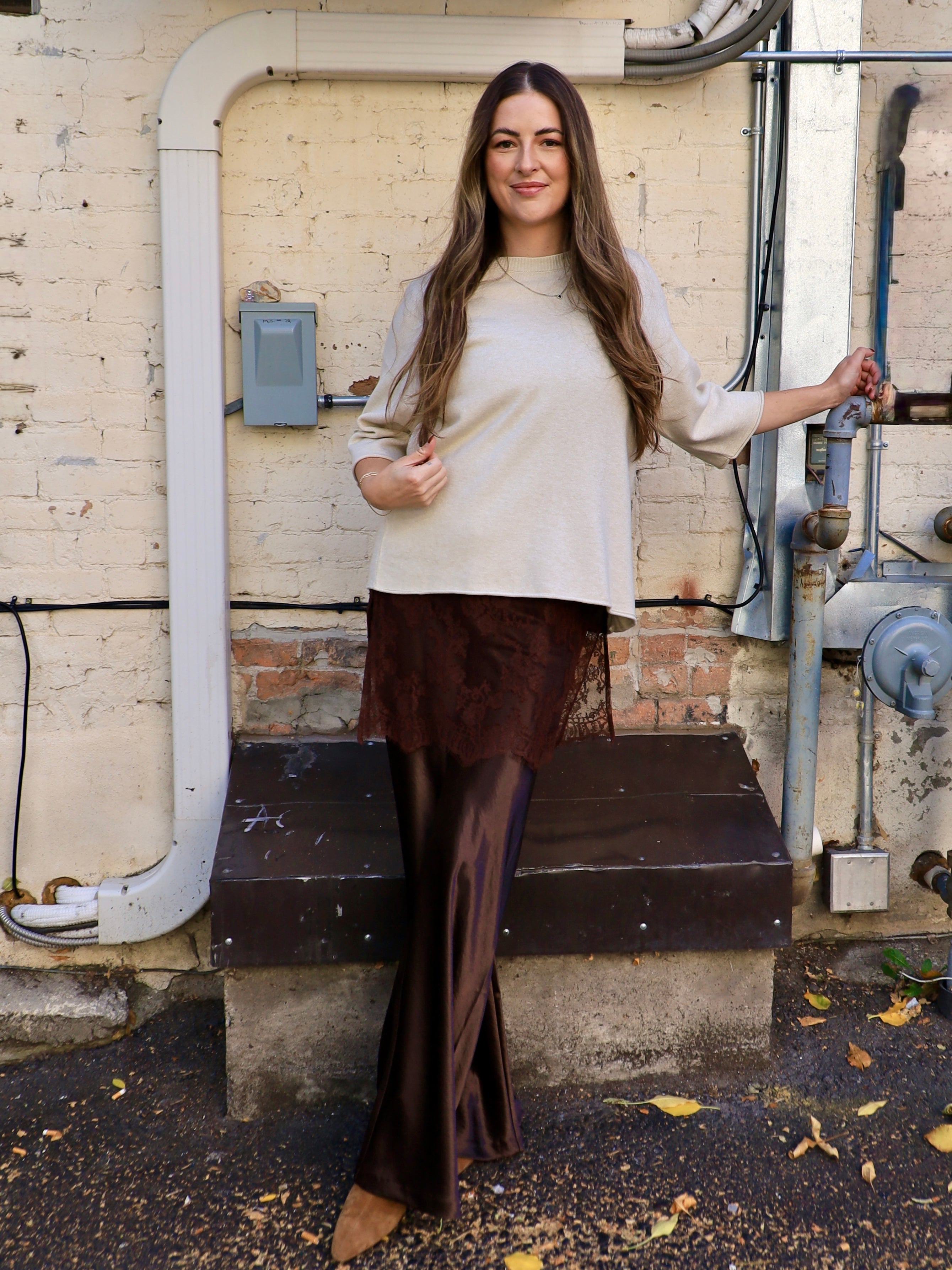Woman wearing cropped oatmeal sweater top with bell sleeves and lace hem detail