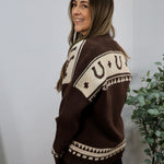 Brown and cream knit cardigan with horseshoe pattern, modeled from the back, showing geometric western-inspired design.