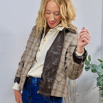Plaid blazer jacket with brown leather trim and gold buttons, styled over cream blouse with jeans.