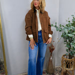 Oversized brown barn jacket styled open over cream blouse and wide-leg blue jeans with brown boots.