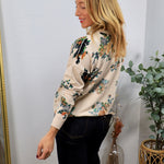 Cream floral cardigan with multicolor blooms, worn over dark jeans, side profile view.