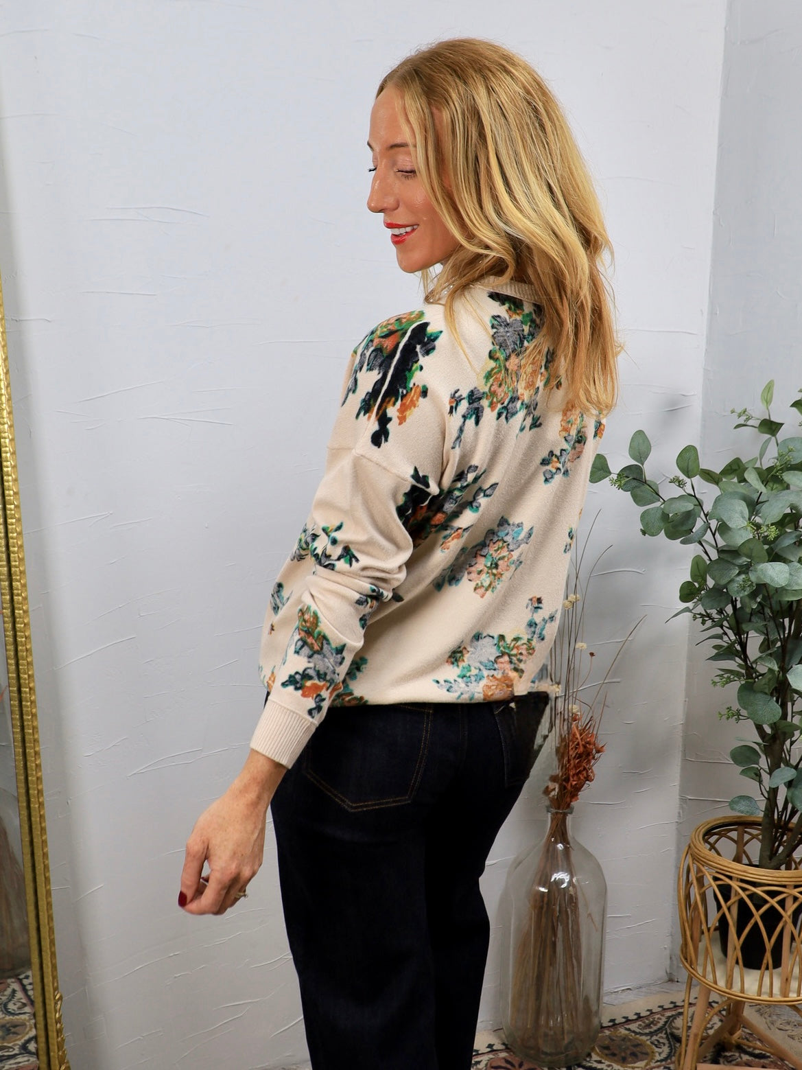 Cream floral cardigan with multicolor blooms, worn over dark jeans, side profile view.
