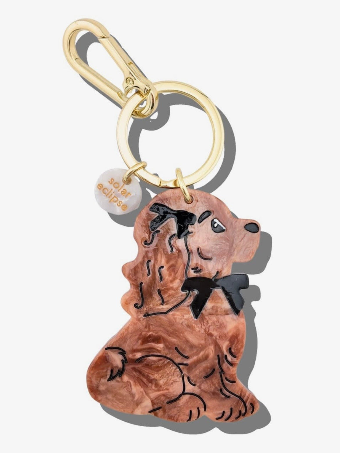 Brown acrylic resin dachshund dog keychain with black bow tie detail and gold carabiner clip.