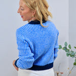 Muse Fitted Cardigan in blue ribbed knit with navy trim, styled with white trousers, back view.