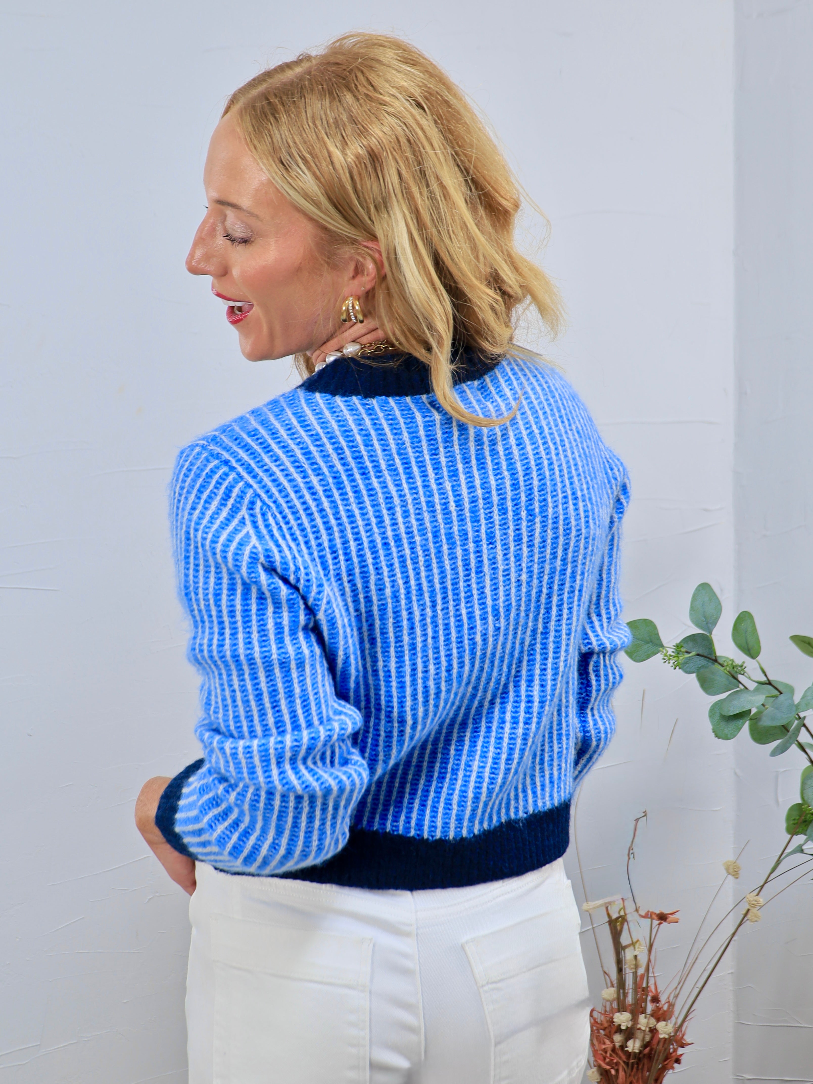 Muse Fitted Cardigan in blue ribbed knit with navy trim, styled with white trousers, back view.